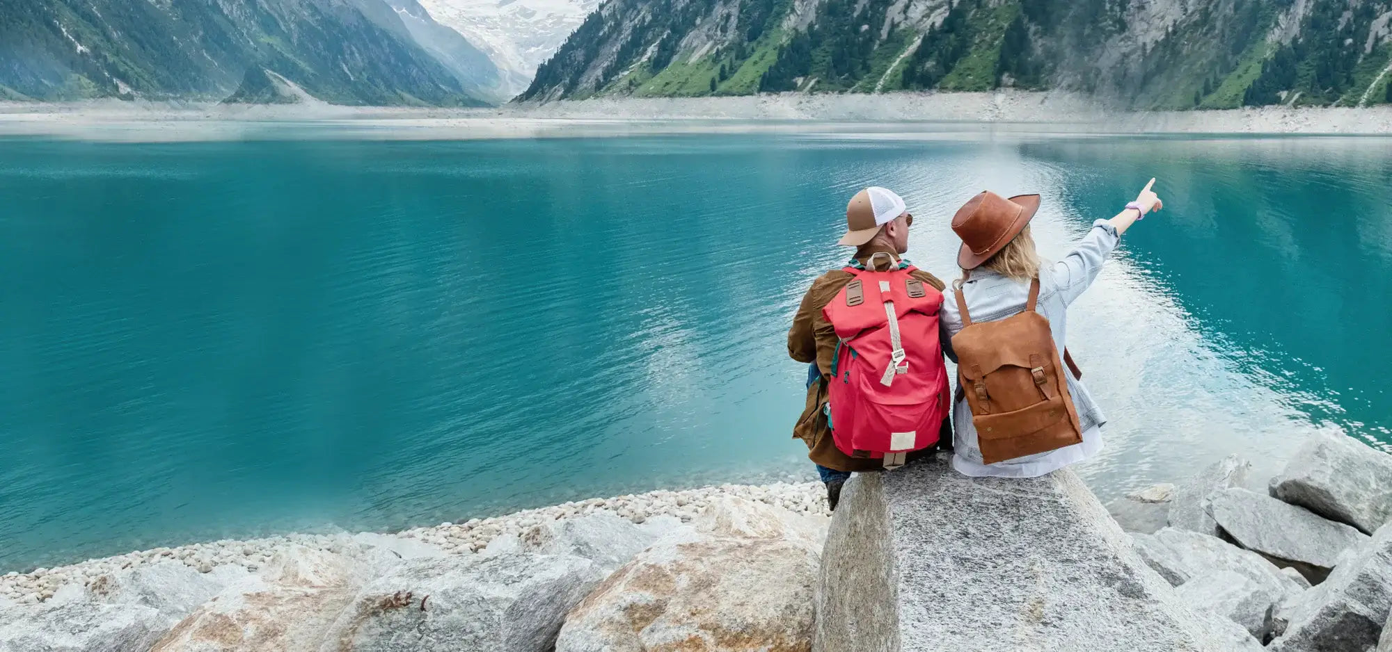 Couple on a road trip pointing at mountain lake, scenic travel destination Canada
